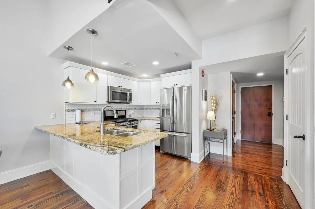 A welcoming kitchen outfitted with a granite countertop, stainless steel appliances, and pendant lighting. The setup is practical yet stylish, perfect for cooking, baking, or enjoying a casual coffee with friends.